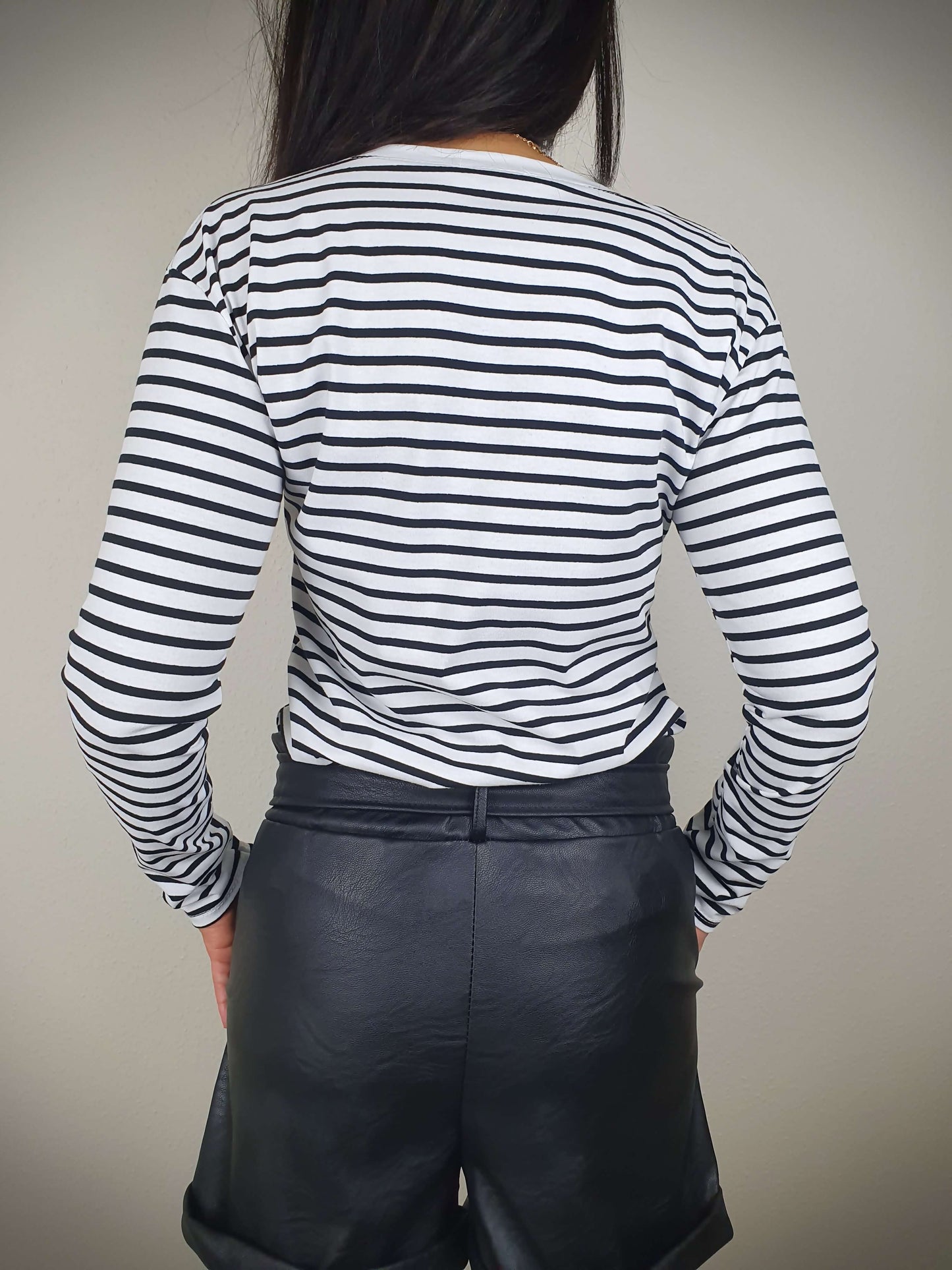 Ce t-shirt rayé noir et blanc à manches longues pour femme présente une coupe droite et un col rond. Les rayures marinières ajoutent une touche chic, tandis que le tissu 100% viscose offre une texture douce. Fabriqué en Italie.