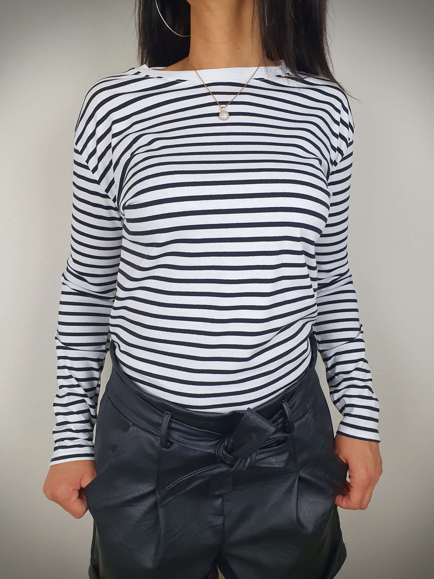 Ce t-shirt rayé noir et blanc à manches longues pour femme présente une coupe droite et un col rond. Les rayures marinières ajoutent une touche chic, tandis que le tissu 100% viscose offre une texture douce. Fabriqué en Italie.