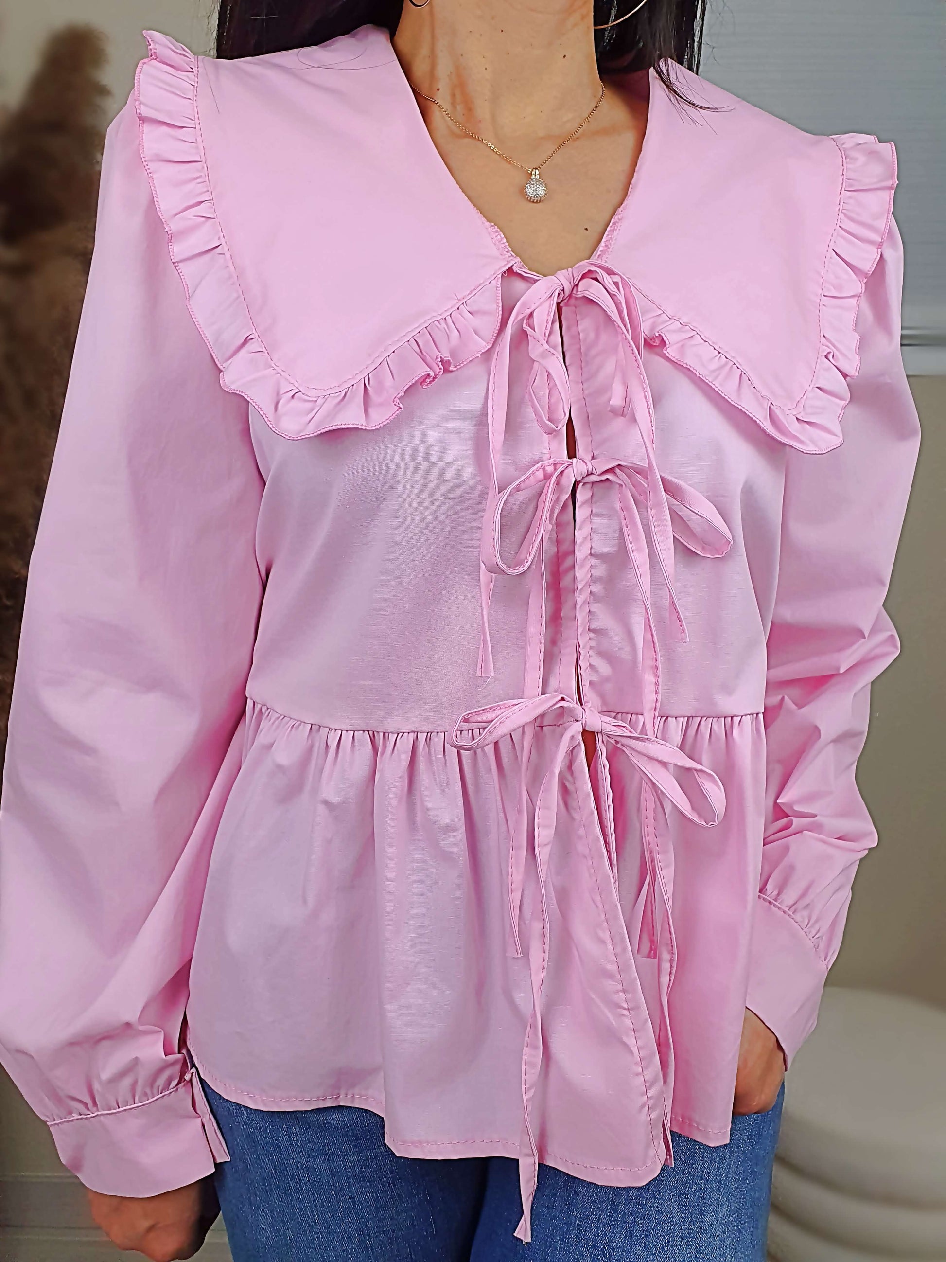 Découvrez notre blouse rose à nouer devant pour femme, avec un col claudine. Ses manches longues et bouffantes sont dotées d'un bouton, et sa coupe légèrement évasée sur le bas apporte une touche élégante. Fermeture avec 3 nœuds sur l'avant. Confectionnée en 100% coton et fabriquée en Italie, elle allie style et confort.