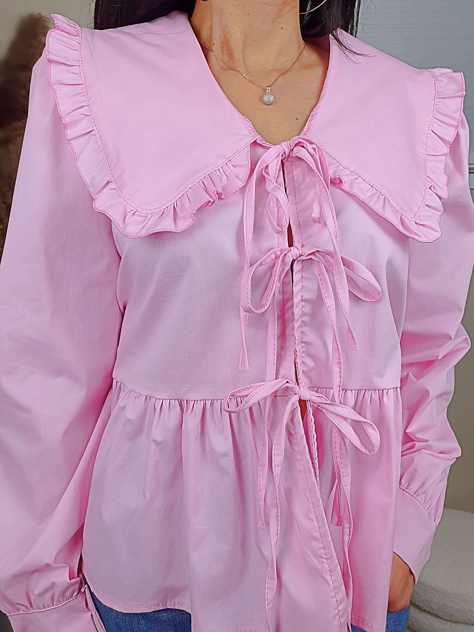 Découvrez notre blouse rose à nouer devant pour femme, avec un col claudine. Ses manches longues et bouffantes sont dotées d'un bouton, et sa coupe légèrement évasée sur le bas apporte une touche élégante. Fermeture avec 3 nœuds sur l'avant. Confectionnée en 100% coton et fabriquée en Italie, elle allie style et confort.