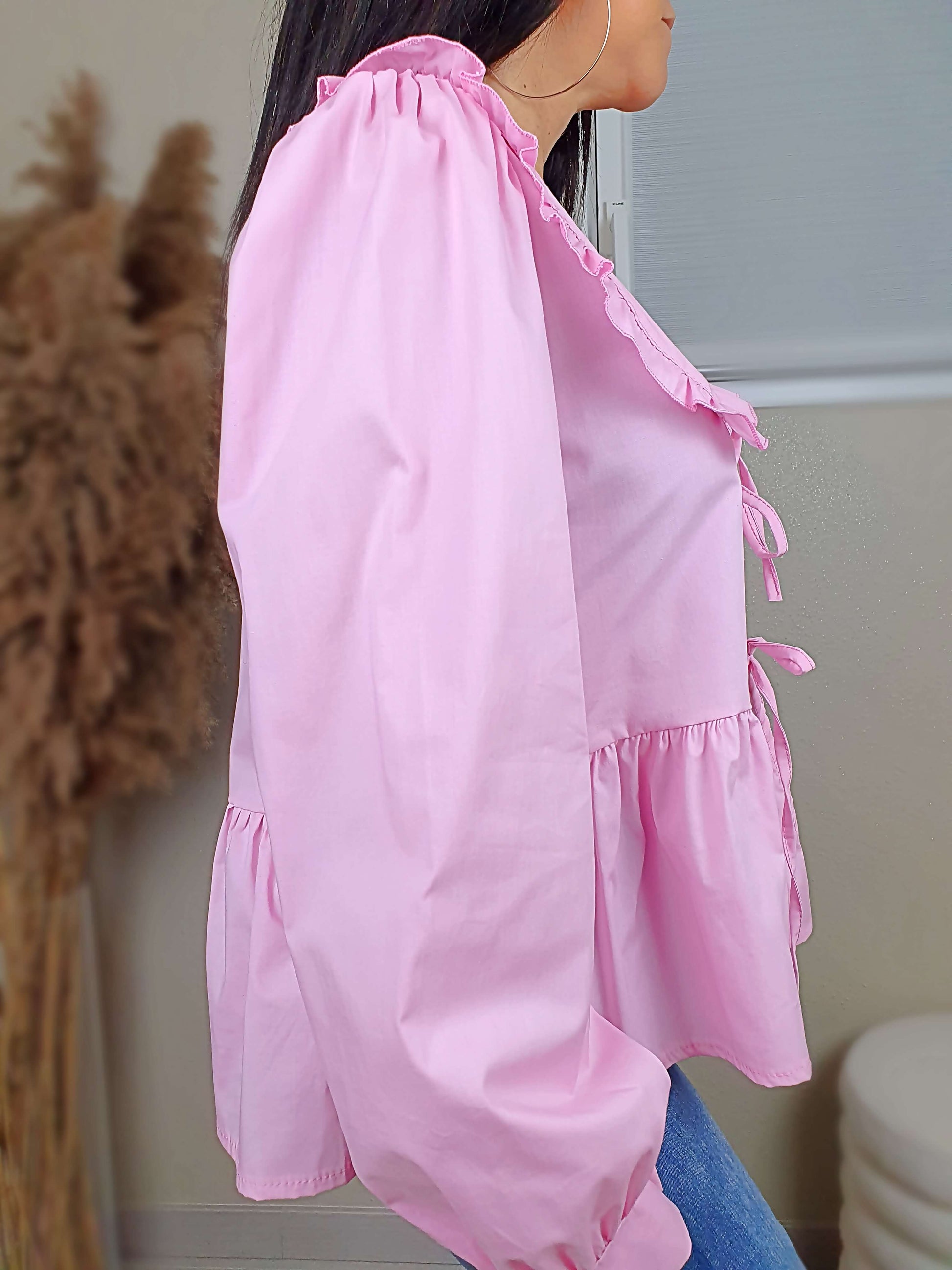 Découvrez notre blouse rose à nouer devant pour femme, avec un col claudine. Ses manches longues et bouffantes sont dotées d'un bouton, et sa coupe légèrement évasée sur le bas apporte une touche élégante. Fermeture avec 3 nœuds sur l'avant. Confectionnée en 100% coton et fabriquée en Italie, elle allie style et confort.