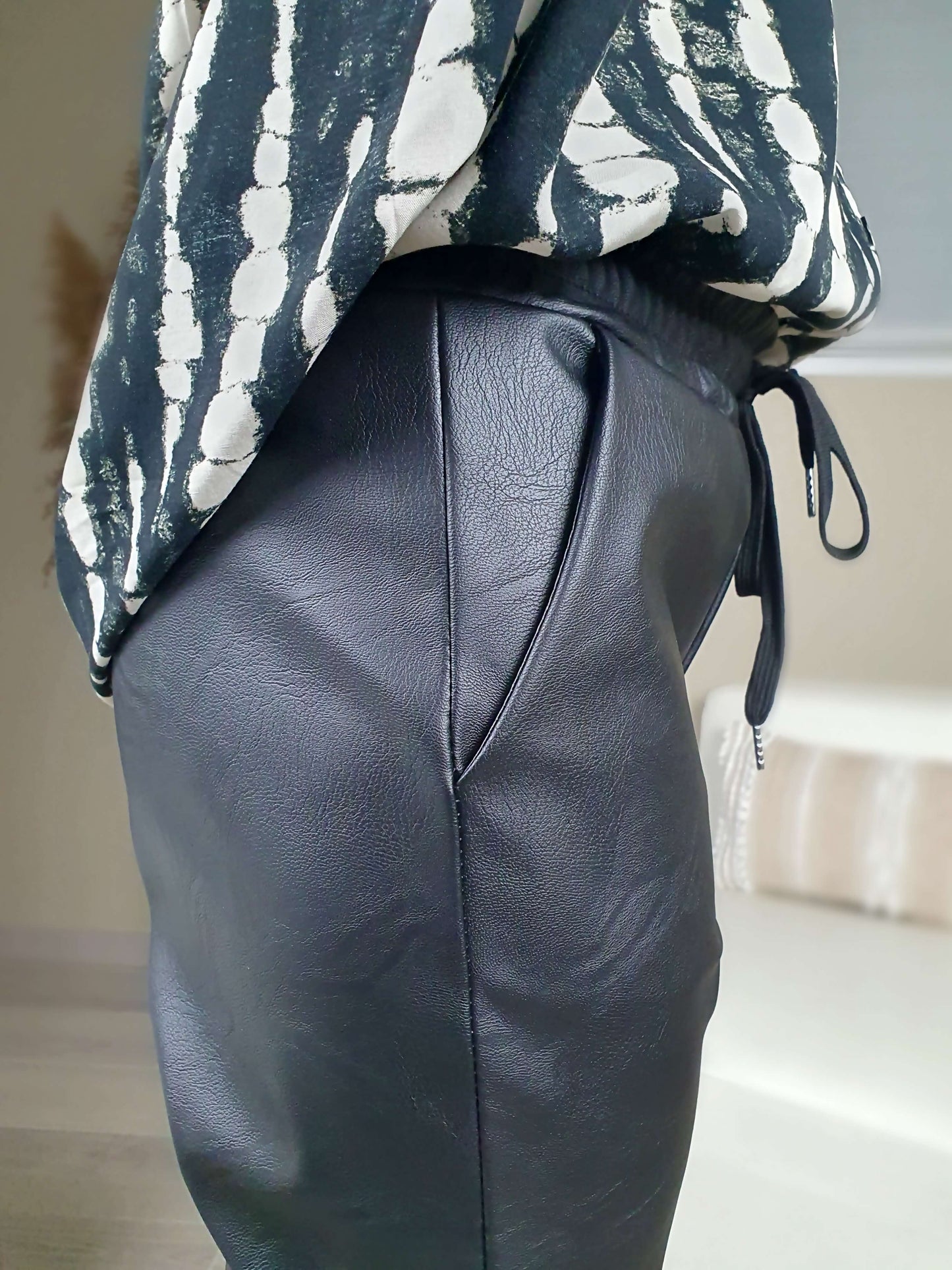 Pantalon simili cuir noir, coupe droite resserrée sur le bas par un élastique avec une poches italienne de chaque coté. La taille du pantalon est élastiquée et ajustable avec lien de serrage. A decouvrir sur www.gayano.fr