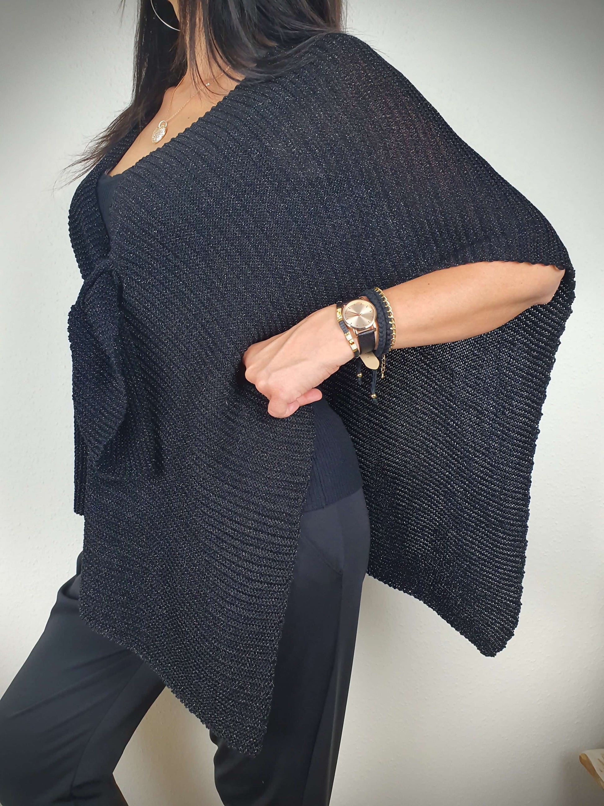 Ce poncho pour femme ample et original est conçu sans manches, se portant sur les épaules. Il se ferme par un passant sur l'avant. Fabriqué en Italie, il est composé d'une maille fine et légère avec 75% de viscose et 25% de fibres métallisées lurex, ajoutant une touche d'éclat.
