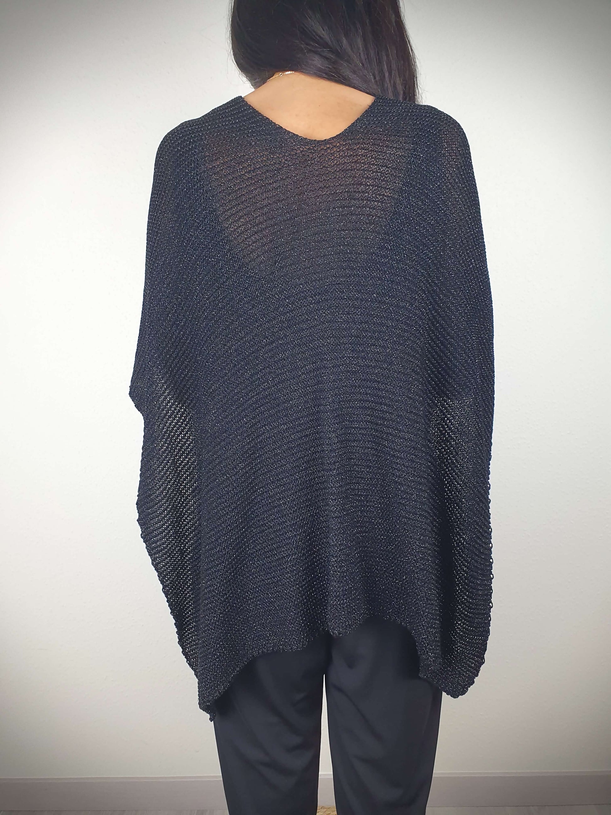 Ce poncho pour femme ample et original est conçu sans manches, se portant sur les épaules. Il se ferme par un passant sur l'avant. Fabriqué en Italie, il est composé d'une maille fine et légère avec 75% de viscose et 25% de fibres métallisées lurex, ajoutant une touche d'éclat.