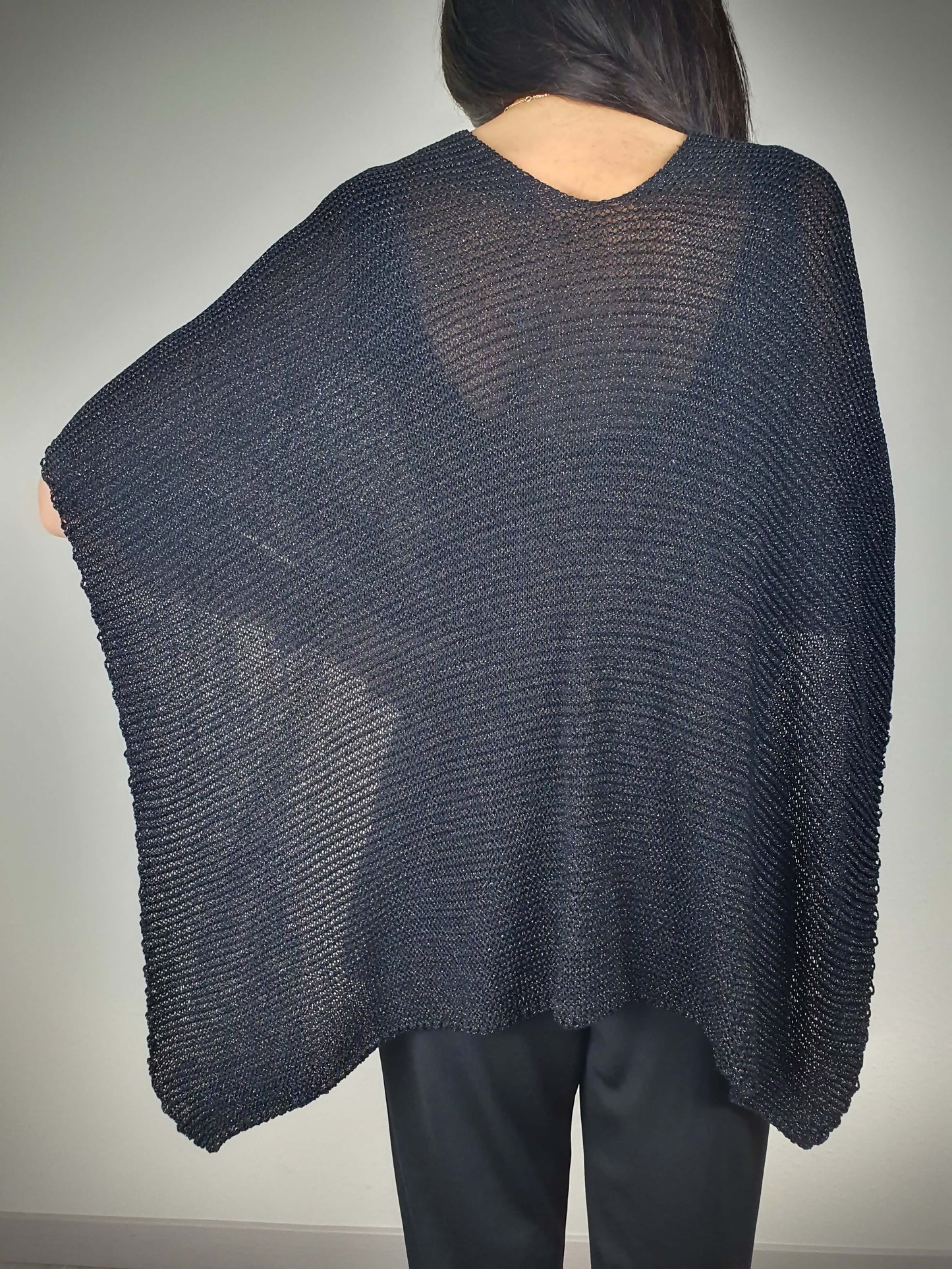 Ce poncho pour femme ample et original est conçu sans manches, se portant sur les épaules. Il se ferme par un passant sur l'avant. Fabriqué en Italie, il est composé d'une maille fine et légère avec 75% de viscose et 25% de fibres métallisées lurex, ajoutant une touche d'éclat.