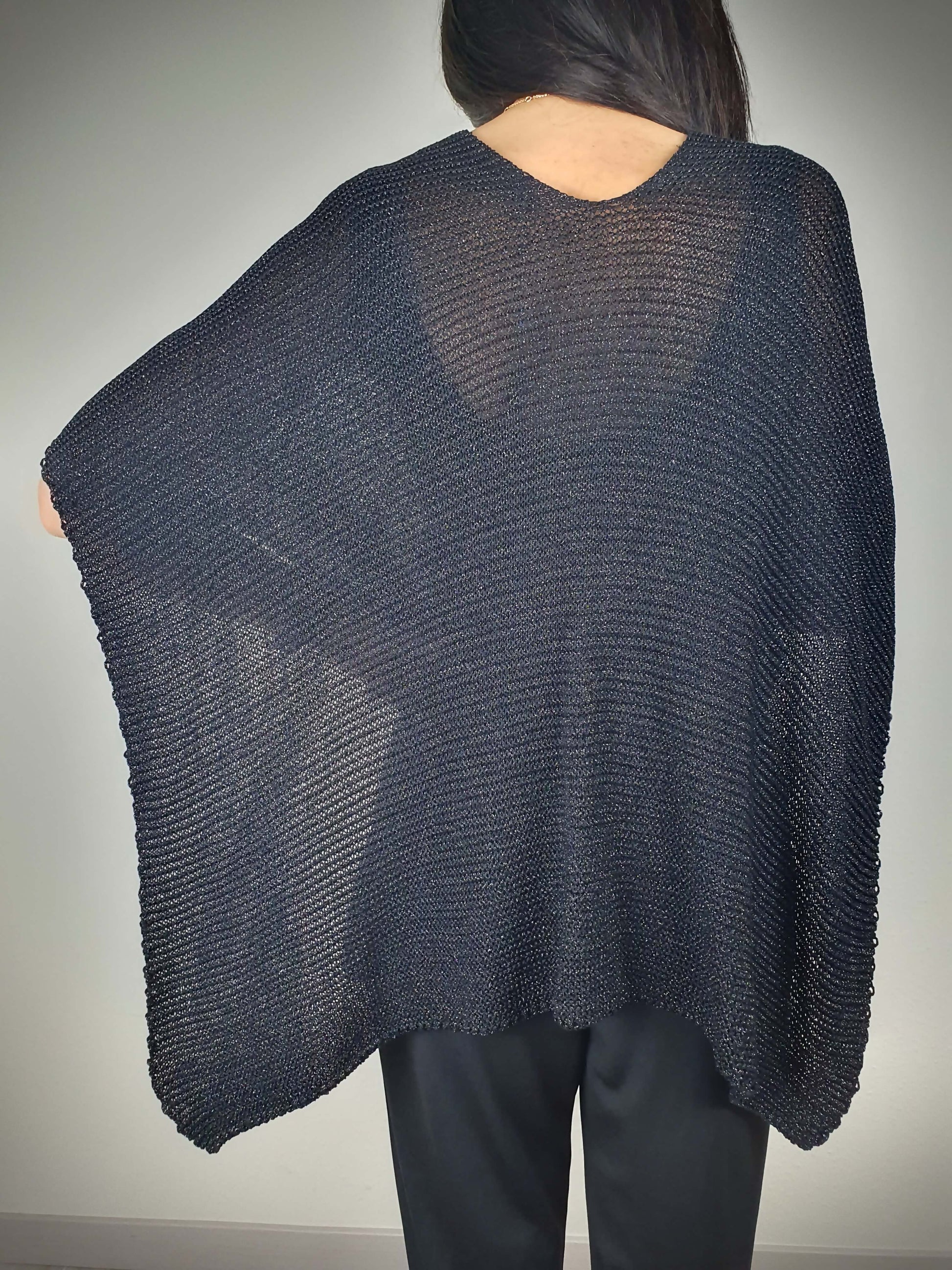 Ce poncho pour femme ample et original est conçu sans manches, se portant sur les épaules. Il se ferme par un passant sur l'avant. Fabriqué en Italie, il est composé d'une maille fine et légère avec 75% de viscose et 25% de fibres métallisées lurex, ajoutant une touche d'éclat.