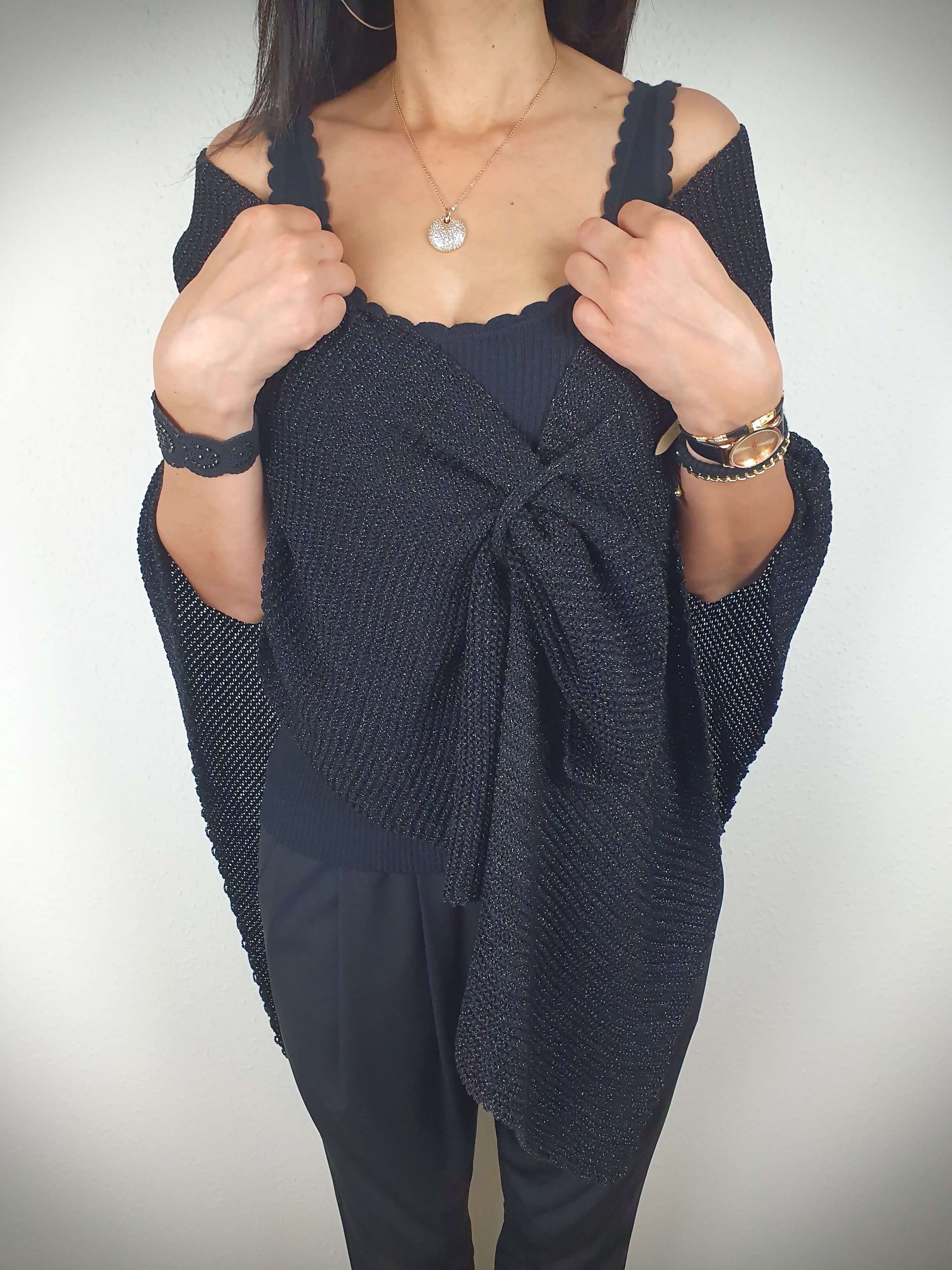Ce poncho pour femme ample et original est conçu sans manches, se portant sur les épaules. Il se ferme par un passant sur l'avant. Fabriqué en Italie, il est composé d'une maille fine et légère avec 75% de viscose et 25% de fibres métallisées lurex, ajoutant une touche d'éclat.