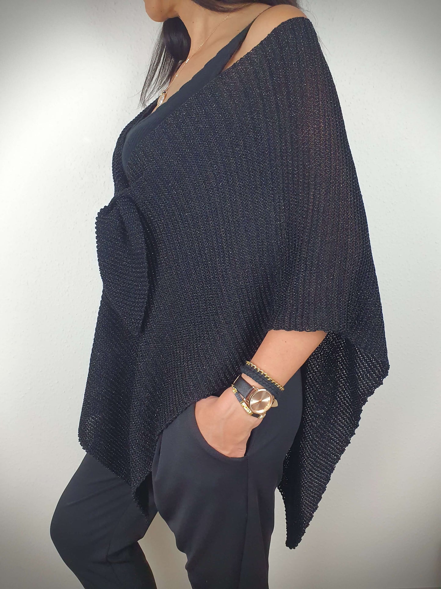 Ce poncho pour femme ample et original est conçu sans manches, se portant sur les épaules. Il se ferme par un passant sur l'avant. Fabriqué en Italie, il est composé d'une maille fine et légère avec 75% de viscose et 25% de fibres métallisées lurex, ajoutant une touche d'éclat.