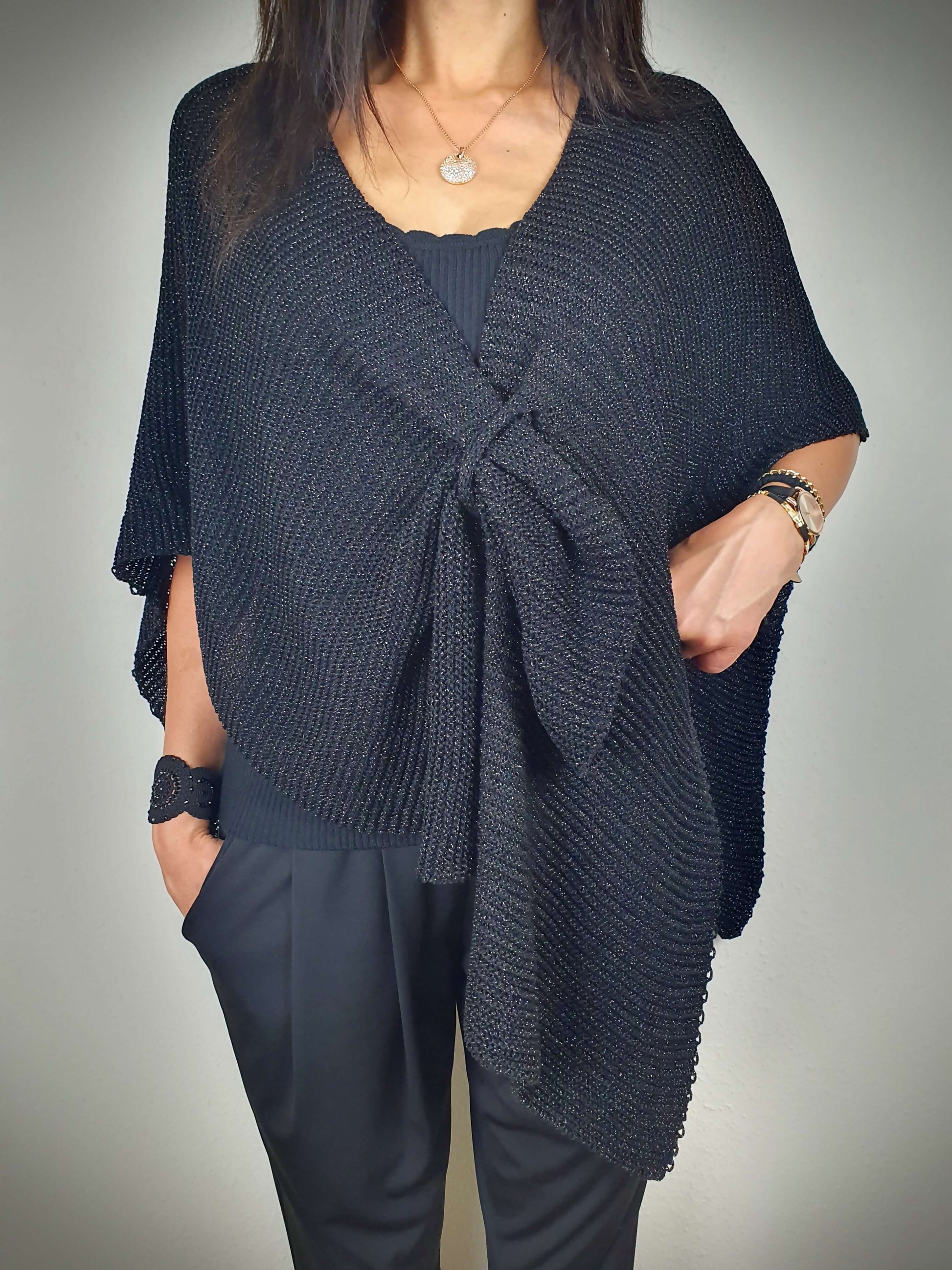 Ce poncho pour femme ample et original est conçu sans manches, se portant sur les épaules. Il se ferme par un passant sur l'avant. Fabriqué en Italie, il est composé d'une maille fine et légère avec 75% de viscose et 25% de fibres métallisées lurex, ajoutant une touche d'éclat.