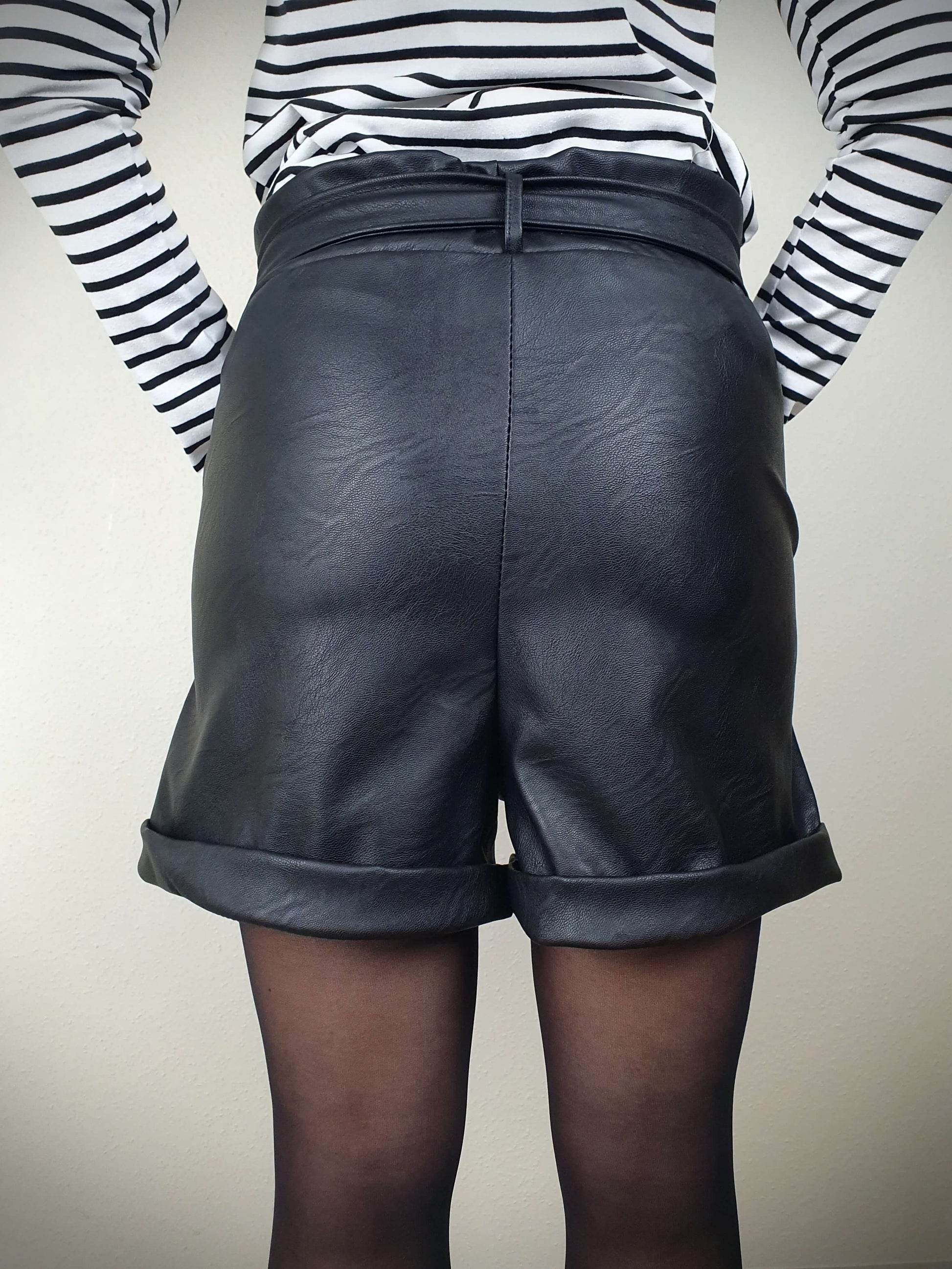 Découvrez ce court en simili cuir noir pour femme, avec une coupe droite flatteuse, taille élastiquée, ceinture à nouer et poches italiennes. Les pinces avant offrent une silhouette élégante, tandis que les revers ajoutent une touche tendance. Fabriqué en Italie avec 45% polyester et 55% polyuréthane pour une qualité exceptionnelle.