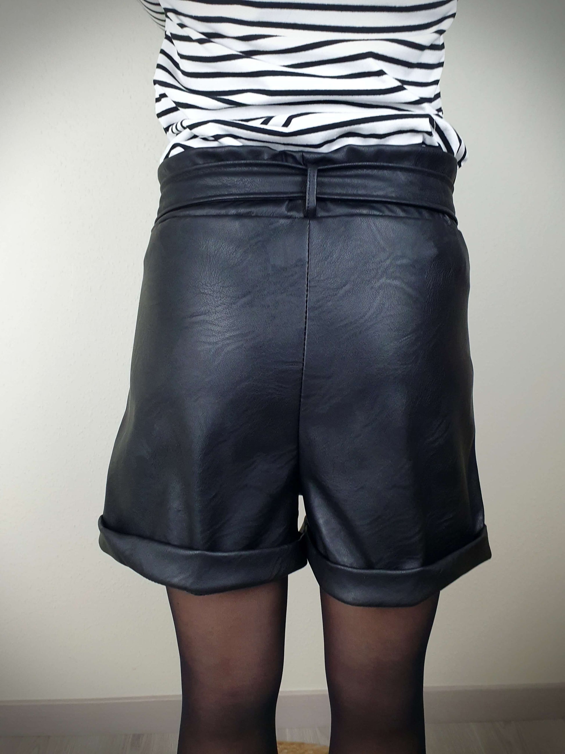 Découvrez ce court en simili cuir noir pour femme, avec une coupe droite flatteuse, taille élastiquée, ceinture à nouer et poches italiennes. Les pinces avant offrent une silhouette élégante, tandis que les revers ajoutent une touche tendance. Fabriqué en Italie avec 45% polyester et 55% polyuréthane pour une qualité exceptionnelle.