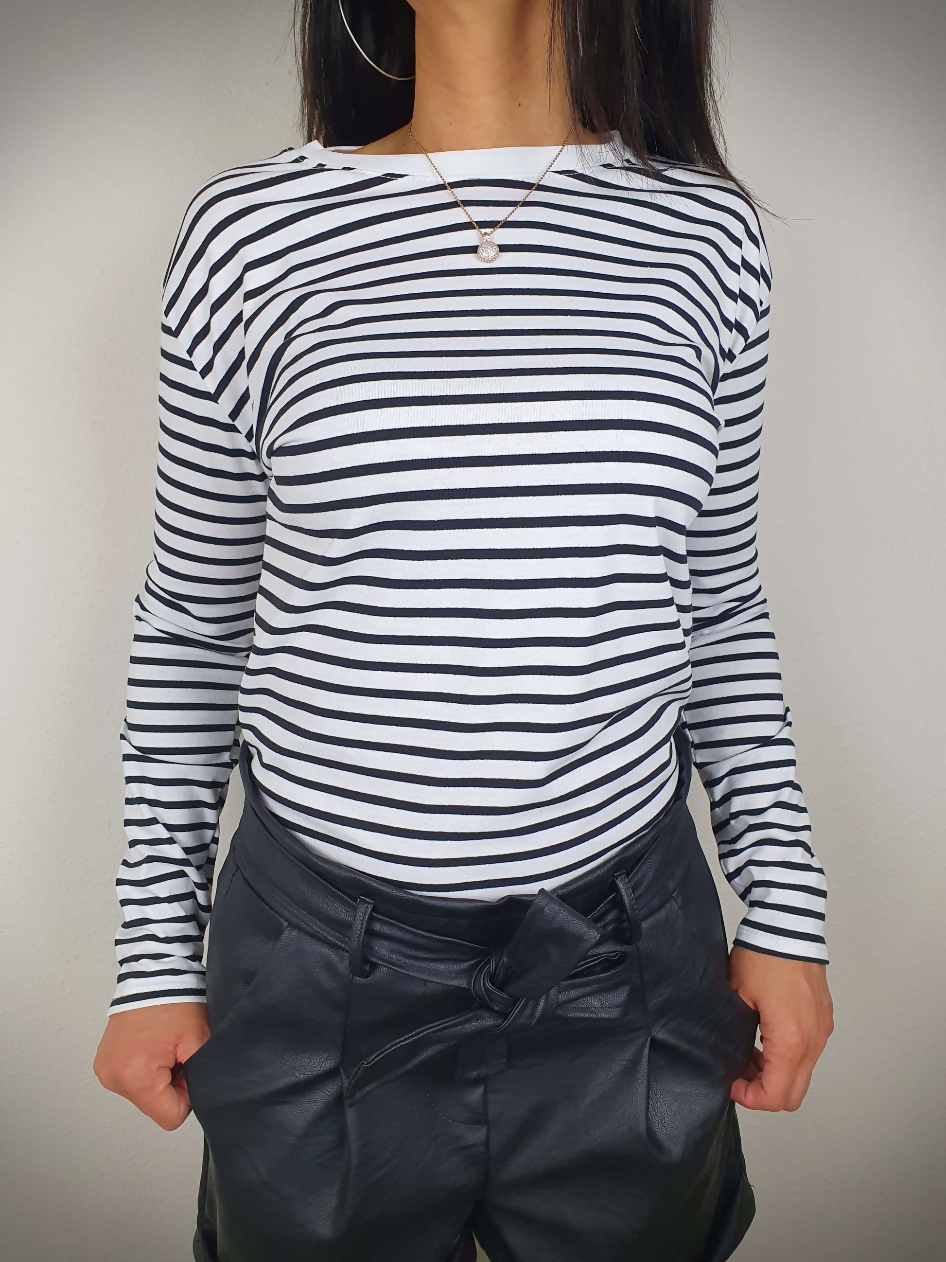 Ce t-shirt rayé noir et blanc à manches longues pour femme présente une coupe droite et un col rond. Les rayures marinières ajoutent une touche chic, tandis que le tissu 100% viscose offre une texture douce. Fabriqué en Italie.