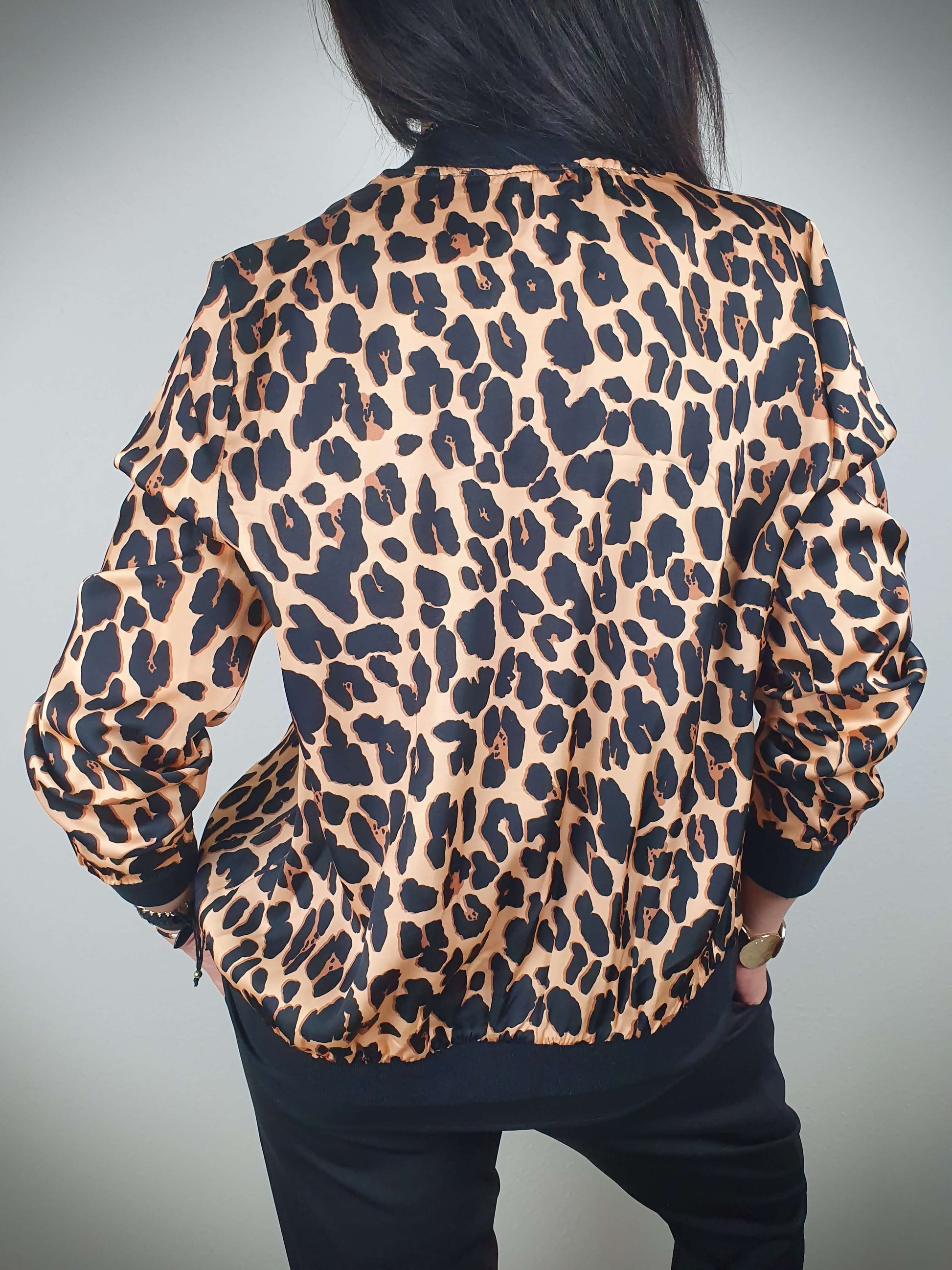 "Cette veste imprimée léopard est un véritable incontournable. Son style intemporel est rehaussé par son col, ses poignets et sa taille côtelés. Les manches longues ajoutent une touche de sophistication. Fabriquée en Italie, elle est confectionnée dans un tissu doux et satiné composé à 80% de viscose et à 20% de satin, offrant un confort luxueux. La fermeture zippée sur l'avant facilite son enfilage."