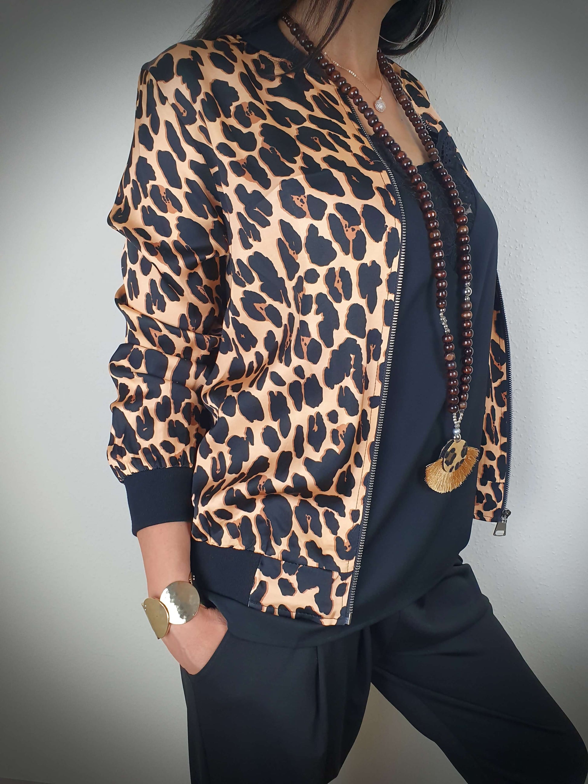 "Cette veste imprimée léopard est un véritable incontournable. Son style intemporel est rehaussé par son col, ses poignets et sa taille côtelés. Les manches longues ajoutent une touche de sophistication. Fabriquée en Italie, elle est confectionnée dans un tissu doux et satiné composé à 80% de viscose et à 20% de satin, offrant un confort luxueux. La fermeture zippée sur l'avant facilite son enfilage."