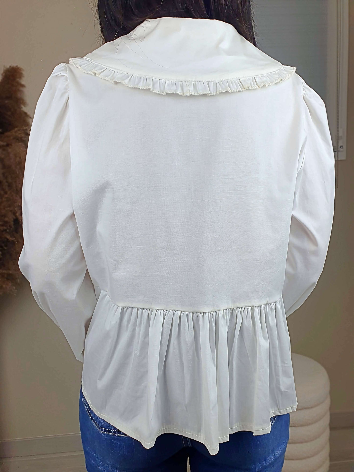 Découvrez notre blouse blanche à nouer devant pour femme, avec un col claudine. Ses manches longues et bouffantes sont dotées d'un bouton, et sa coupe légèrement évasée sur le bas apporte une touche élégante. Fermeture avec 3 nœuds sur l'avant. Confectionnée en 100% coton et fabriquée en Italie, elle allie style et confort.